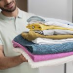 man-holding-pile-clean-clothes